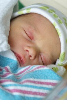 A newborn baby boy is swaddled in his bed a day after his birth.