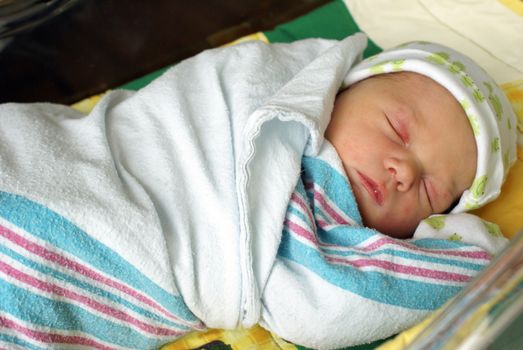 A newborn baby boy is swaddled in his bed a day after his birth.