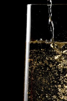 flute of champagne with golden bubbles on black background and space for text