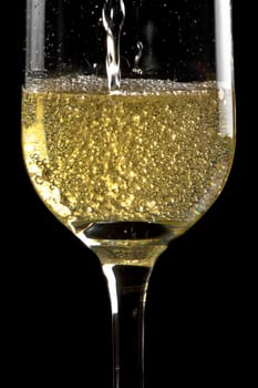 begin filling a flute of champagne with golden bubbles on black background