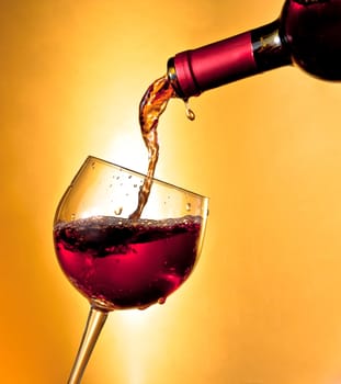 pouring red wine in the glass tilted on golden background