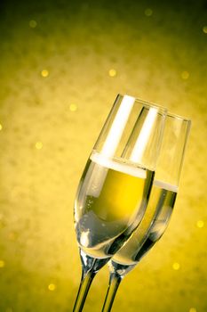 flutes of champagne on golden bokeh background with space for text