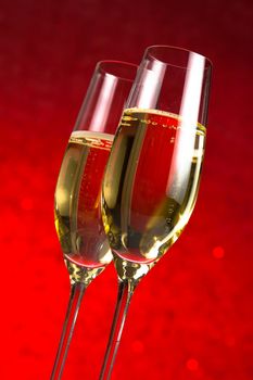 a pair of flutes of champagne on red bokeh background