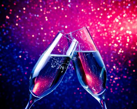 pair of a champagne flutes with bubbles make cheers on blue tint light bokeh background
