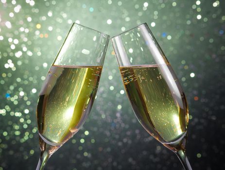 pair of a champagne flutes with gold bubbles make cheers on green light bokeh background