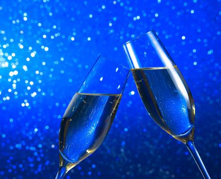 champagne flutes make cheers on blue light bokeh background with space for text