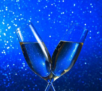 champagne flutes on blue light bokeh background with space for text