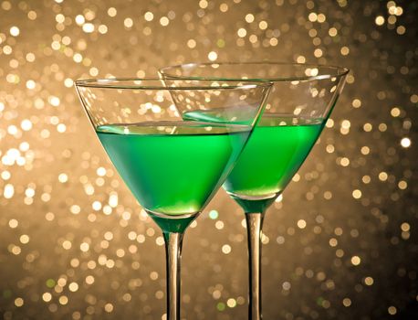 glasses of green cocktail on dark tint light bokeh background on table