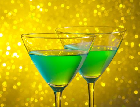 glasses of green cocktail on golden tint light bokeh background