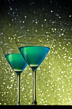 glasses of blue cocktail on golden tint light bokeh background on table