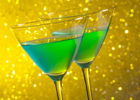 two glasses of green cocktail on golden tint light bokeh background