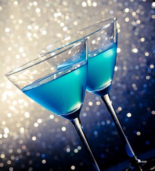 two glasses of blue cocktail on white and dark tint light bokeh background