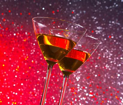 view from below of glasses of cocktail on red and violet tint light bokeh background on bar table