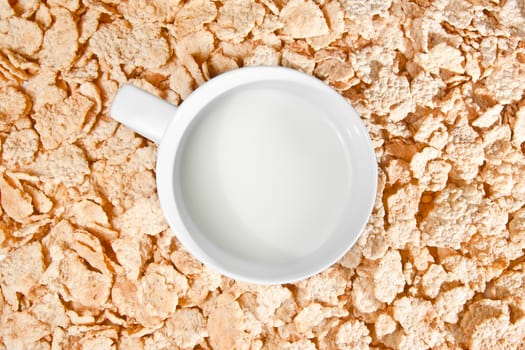 top of view of cup of milk on corn flakes background, breakfast concept