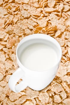 top of view of cup of milk on corn flakes background, breakfast concept