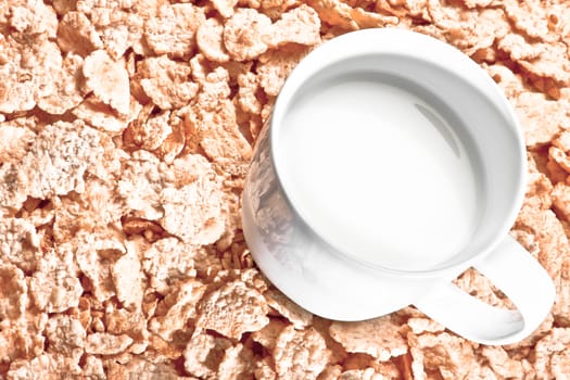 top of view of cup of milk on corn flakes background, diet concept