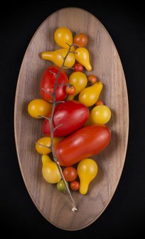 Organic garden Red and yellow cherry tomatoes on a wooden bowl isolated on black
