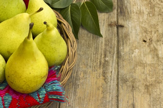 Fresh, juicy pears in a wicker bowl on a wooden background