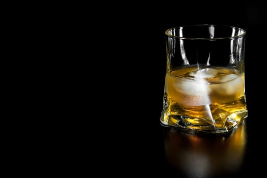 glass of whiskey with ice  with space for text on black background