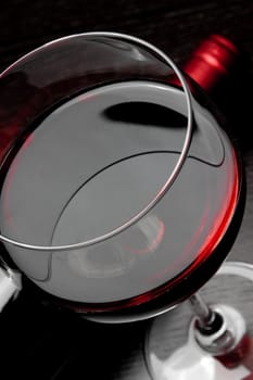 top of view of red wine glass near bottle on black wood table
