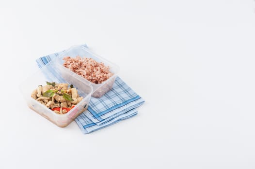 Stir freid basil with chicken breast and Termitomyces cooked by clean food concept with brown rice in lunch box isolated on white background with clipping path