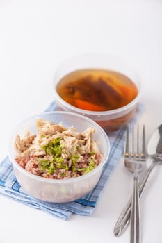 Brown rice gruel with chicken breast with vegetables soup cooked by clean food concept in separate lunch box on white table