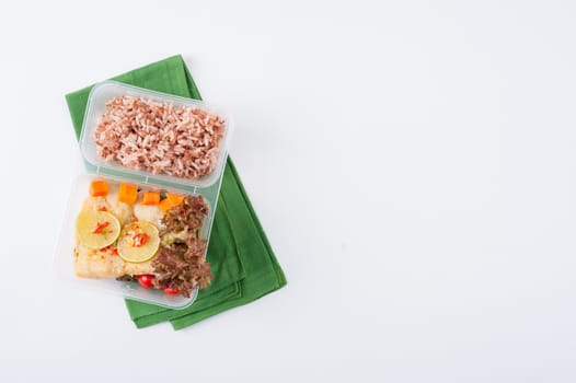 Thai style steamed fish in spicy lemon sauce cooked by clean food concept with vegetables and brown rice in lunch box on white table