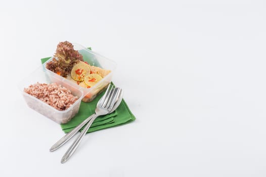 Thai style steamed fish in spicy lemon sauce cooked by clean food concept with vegetables and brown rice in lunch box on white table