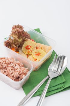Thai style steamed fish in spicy lemon sauce cooked by clean food concept with vegetables and brown rice in lunch box on white table