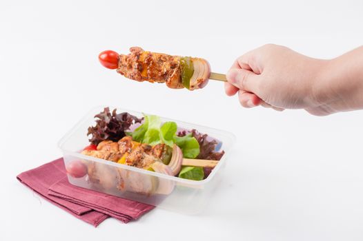 Chicken breast barbecue cooked by clean food concept and vegetables in lunch box with female right hand holding one of them
