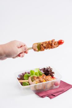 Chicken breast barbecue cooked by clean food concept and vegetables in lunch box with female left hand holding one of them