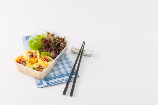 Thai spicy egg rolls (Fresh spring rolls, Kuay Teaw Lui Suan but use egg replace to rice sheet) with tofu, minced pork and vegetables cooked by clean food concept in lunch box on white table