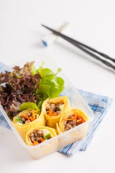 Thai spicy egg rolls (Fresh spring rolls, Kuay Teaw Lui Suan but use egg replace to rice sheet) with tofu, minced pork and vegetables cooked by clean food concept in lunch box on white table