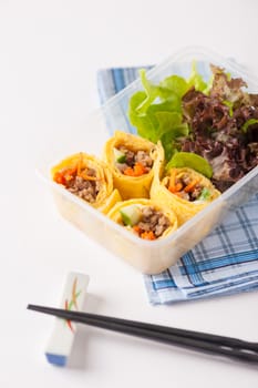 Thai spicy egg rolls (Fresh spring rolls, Kuay Teaw Lui Suan but use egg replace to rice sheet) with tofu, minced pork and vegetables cooked by clean food concept in lunch box on white table