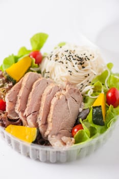 Salad with roasted pork and soba noodles by clean food concept in lunch box on white table