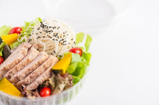 Salad with roasted pork and soba noodles by clean food concept in lunch box on white table