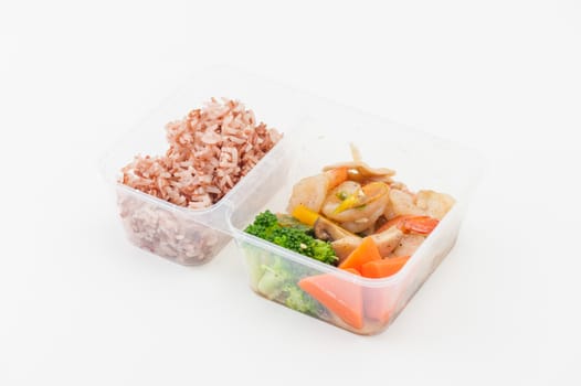 Thai style spicy stir fried shrimps cooked by clean food concept with brown rice and vegetables in lunch box on white table