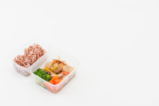 Thai style spicy stir fried shrimps cooked by clean food concept with brown rice and vegetables in lunch box on white table