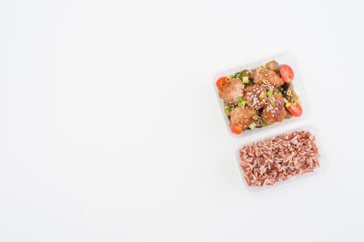 Tsukune (Japanese chicken meatballs) cooked by clean food concept with brown rice in lunch box on white table