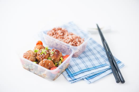 Tsukune (Japanese chicken meatballs) cooked by clean food concept with brown rice in lunch box