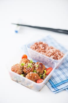 Tsukune (Japanese chicken meatballs) cooked by clean food concept with brown rice in lunch box