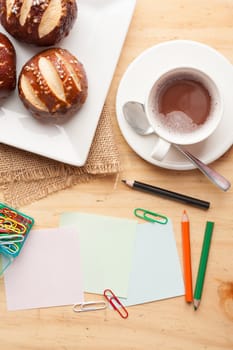 Notebook and sticky paper, paper clip, color pencil, and pen on wood table in vintage style