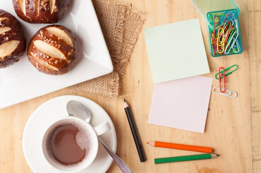 Notebook and sticky paper, paper clip, color pencil, and pen on wood table in vintage style
