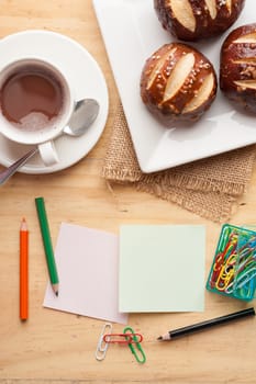 Notebook and sticky paper, paper clip, color pencil, and pen on wood table in vintage style