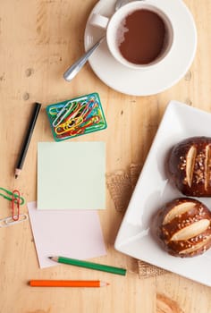 Notebook and sticky paper, paper clip, color pencil, and pen on wood table in vintage style
