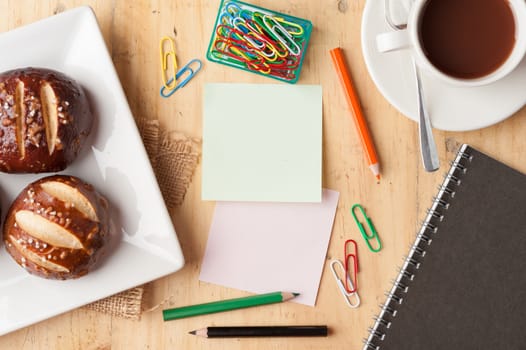 Notebook and sticky paper, paper clip, color pencil, and pen on wood table in vintage style