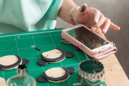 female hand touching smartphone while making fondant cake, fondant sugar mod action