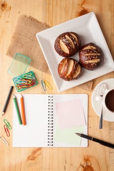 Notebook and sticky paper, paper clip, color pencil, and pen on wood table in vintage style
