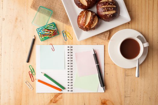 Notebook and sticky paper, paper clip, color pencil, and pen on wood table in vintage style