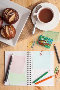 Notebook and sticky paper, paper clip, color pencil, and pen on wood table in vintage style